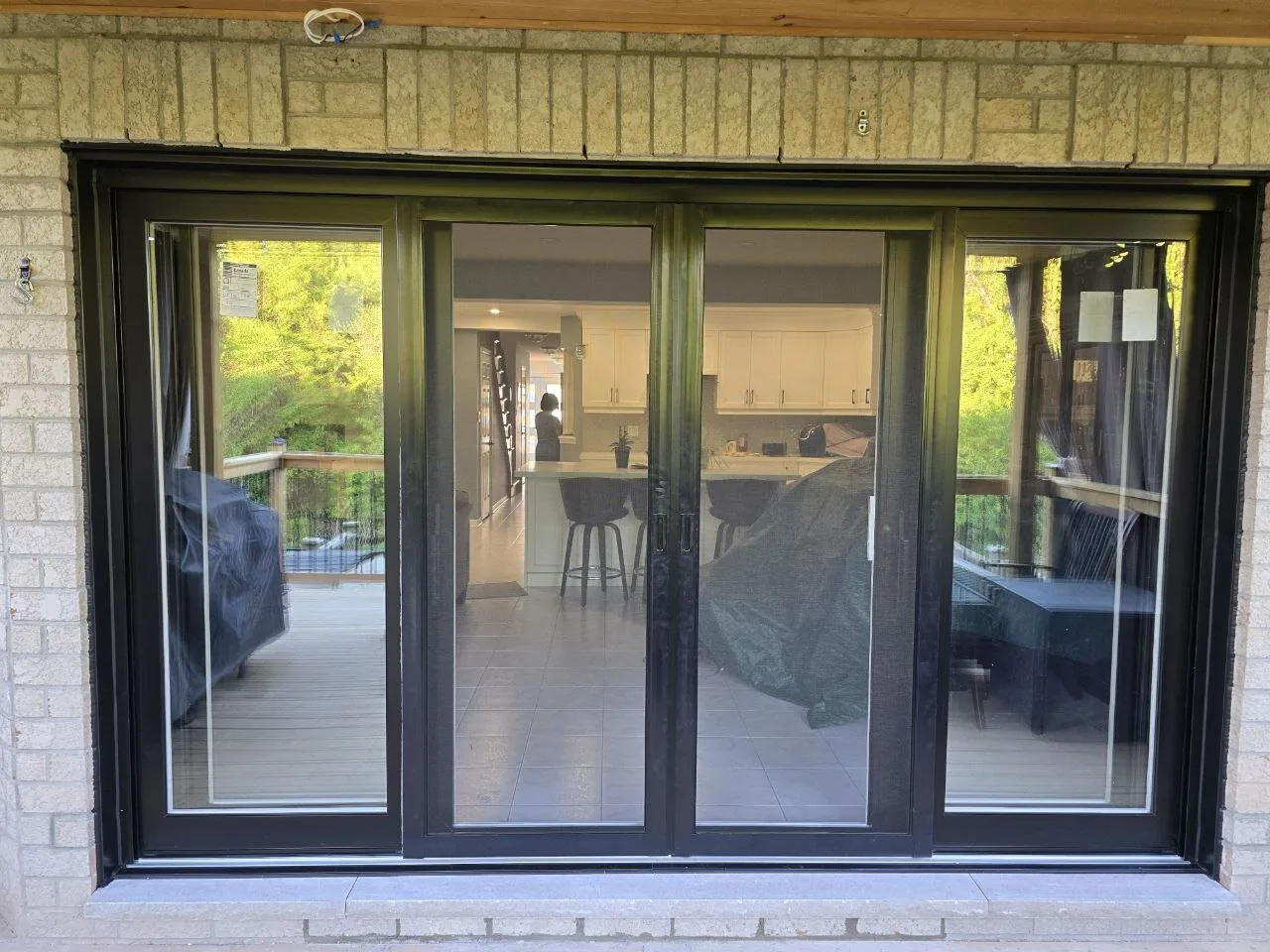 After: black multi-panel patio door installed in the same brick wall