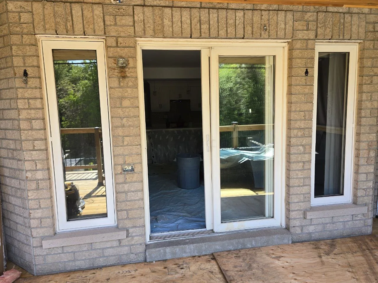 Before: old white patio door with sidelites in a brick wall